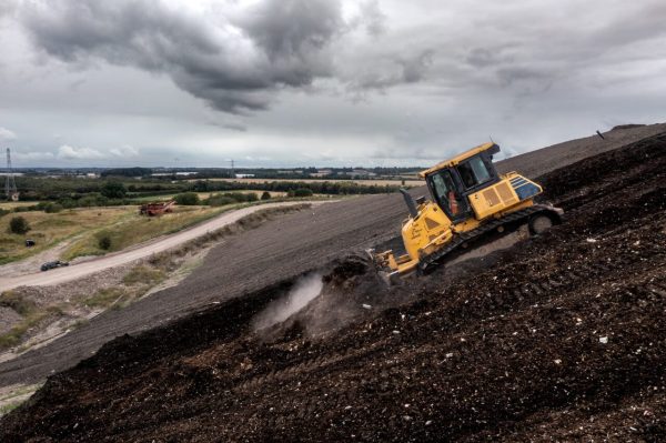 a bulldozer on a slope moving waste on a landfill site 1