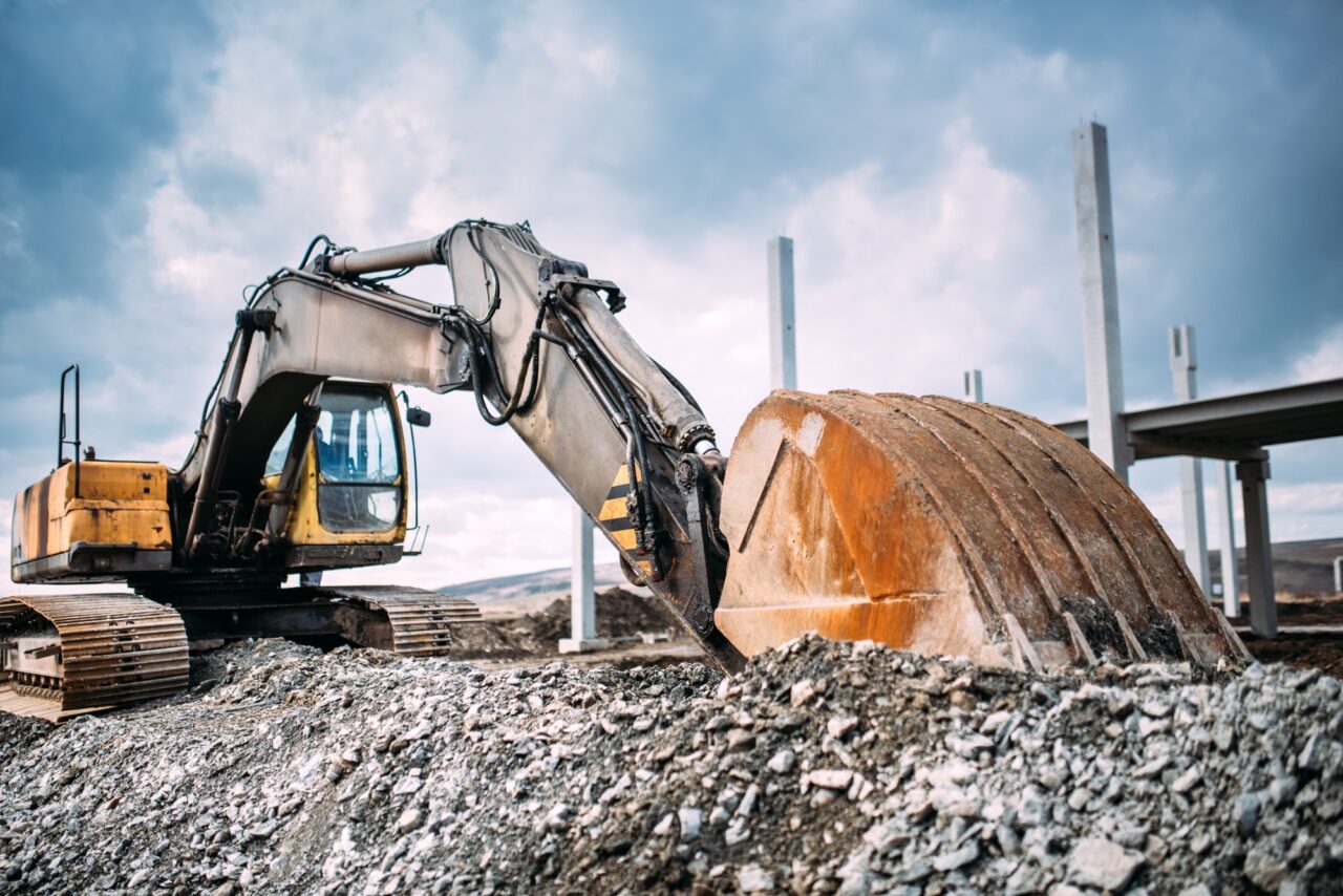 industrial heavy duty excavator moving gravel on highway construction site